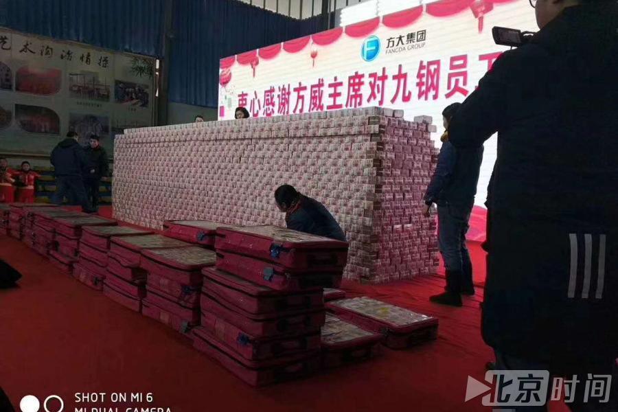 视频中,红地毯上是一叠叠百元砌成的"现金墙",后面悬挂着一条横幅
