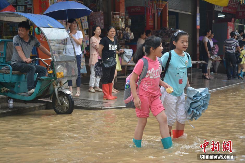 小学生自己穿着雨鞋蹚水上学.