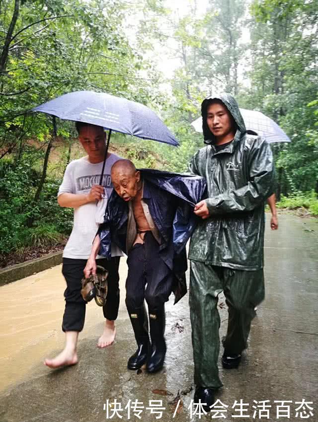 工作队员陈显健二话不说,脱下自己的雨靴给老人换上,而自己打赤脚行走