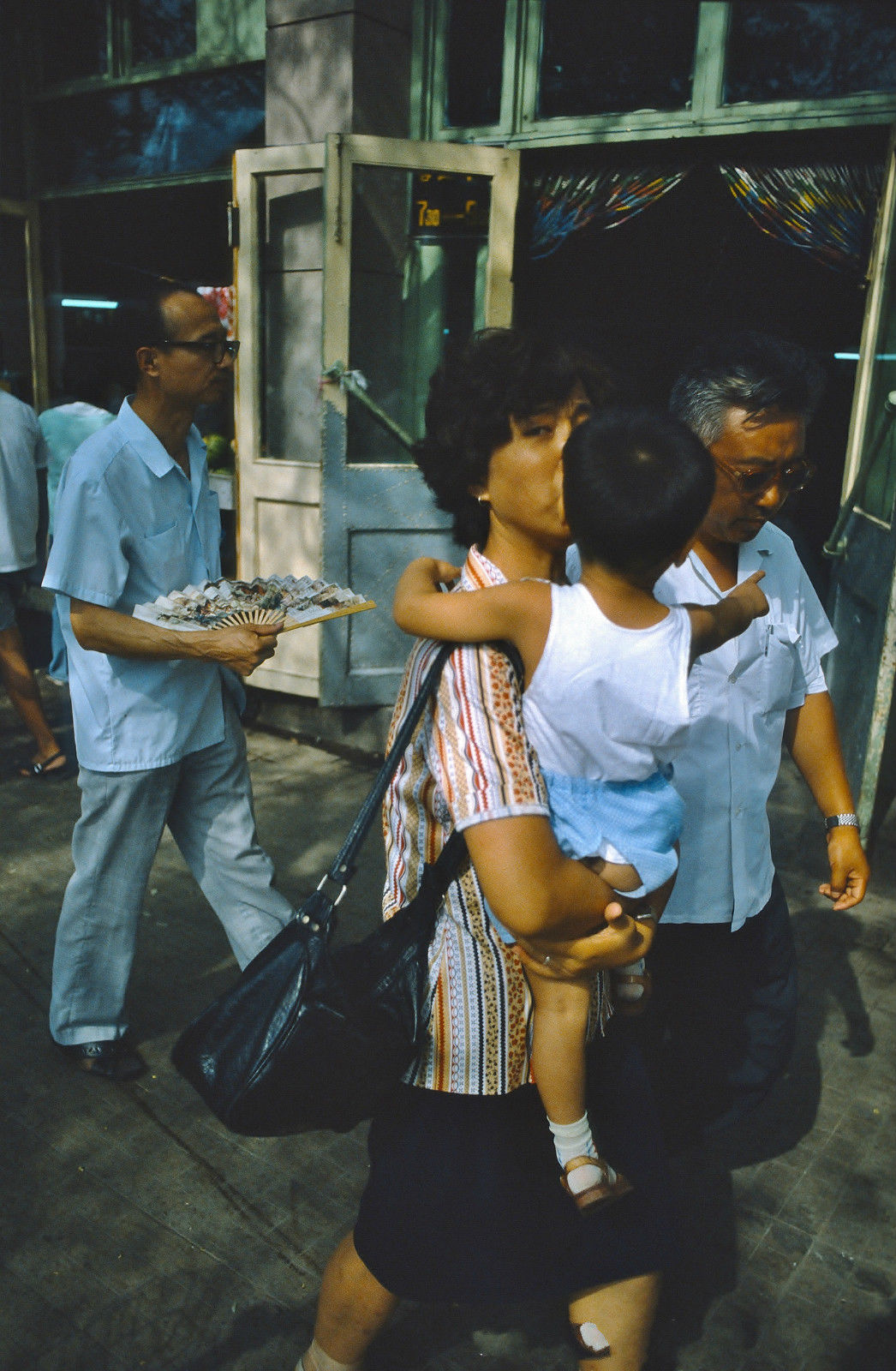 1987年前的夏天中午,妇女抱着穿开裆裤孩子的走在北京大街上,后面一个