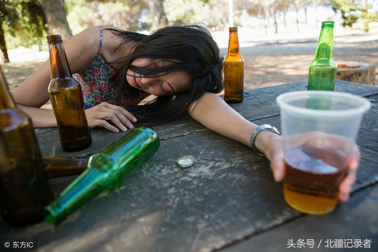 一名醉酒女子趴在桌子上,仍不忘拿着酒杯.(图片来自东方ic)