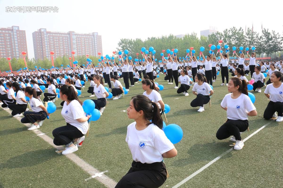 科技学院的千名女生,手持彩扇和蓝色气球,在表演现场不停的变换队形