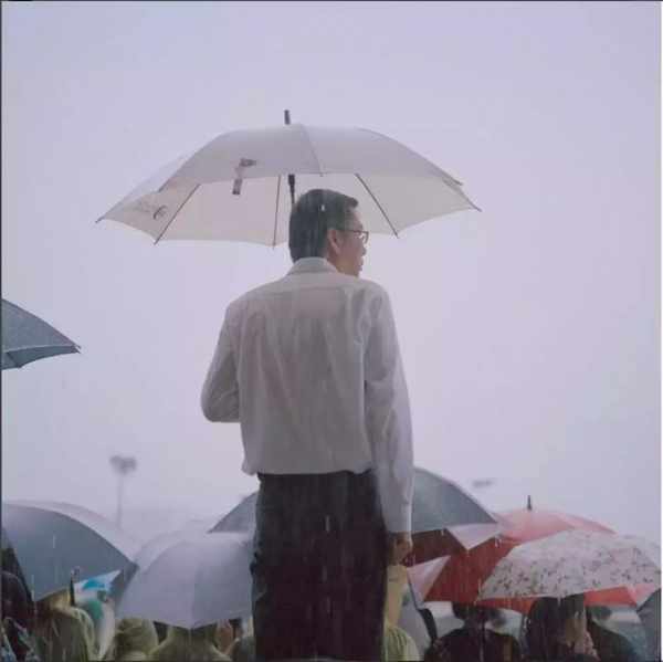 (雨中撑着伞的中年男人,被淋湿的背影即将淹没在人海中.)