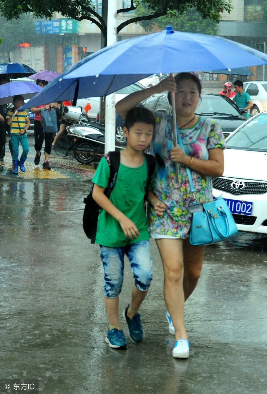 在浙江省武义县实验小学门前,许多家长暴雨中送小孩上学.