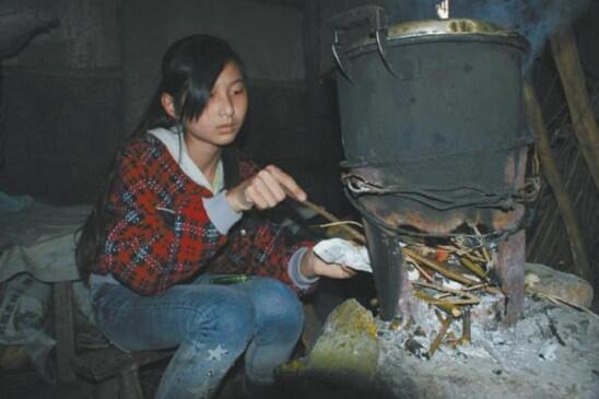 图中的小女孩正在烧火煮开水!