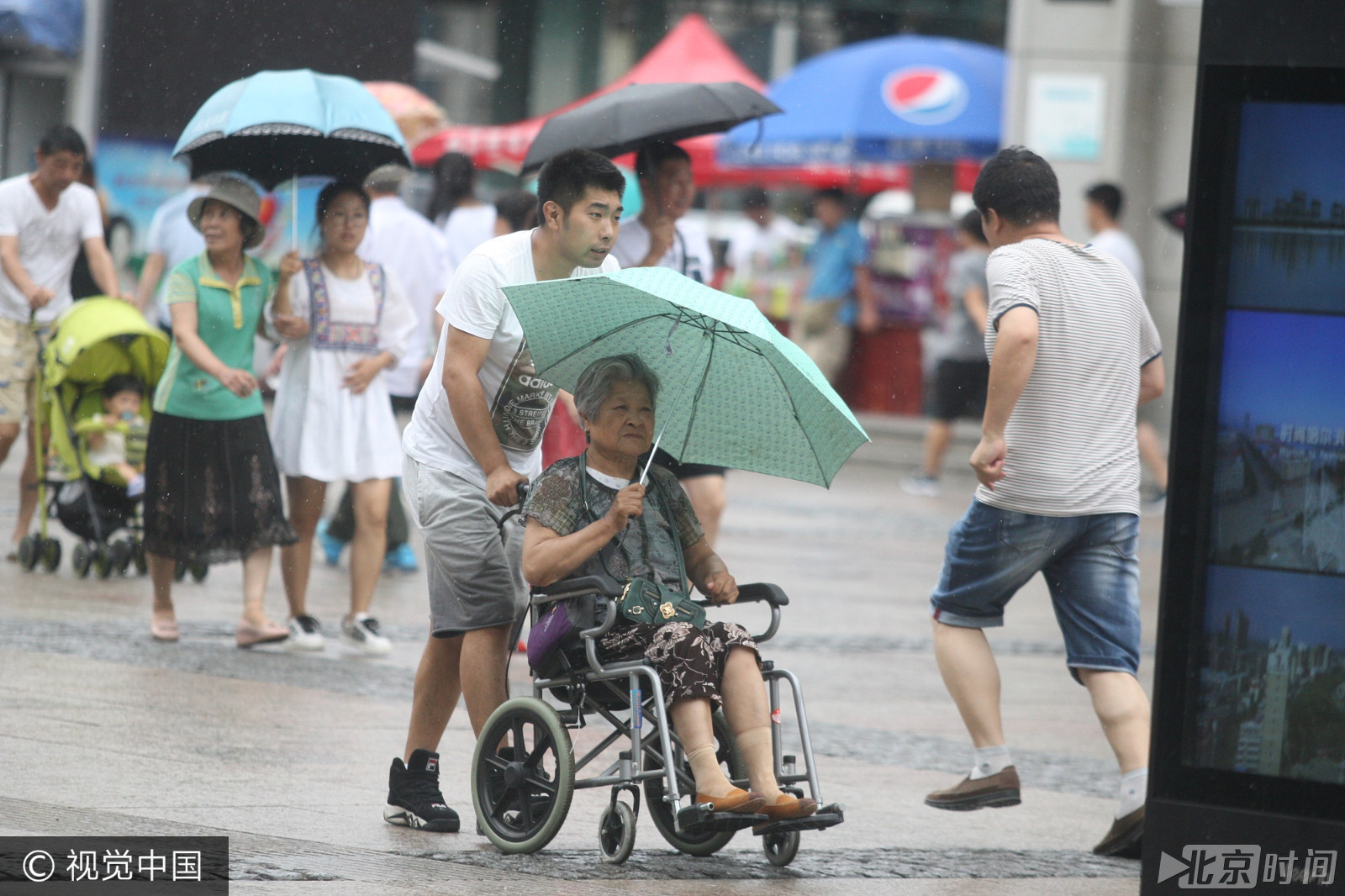 哈尔滨大雨突袭 男子雨中为老人撑伞获称赞