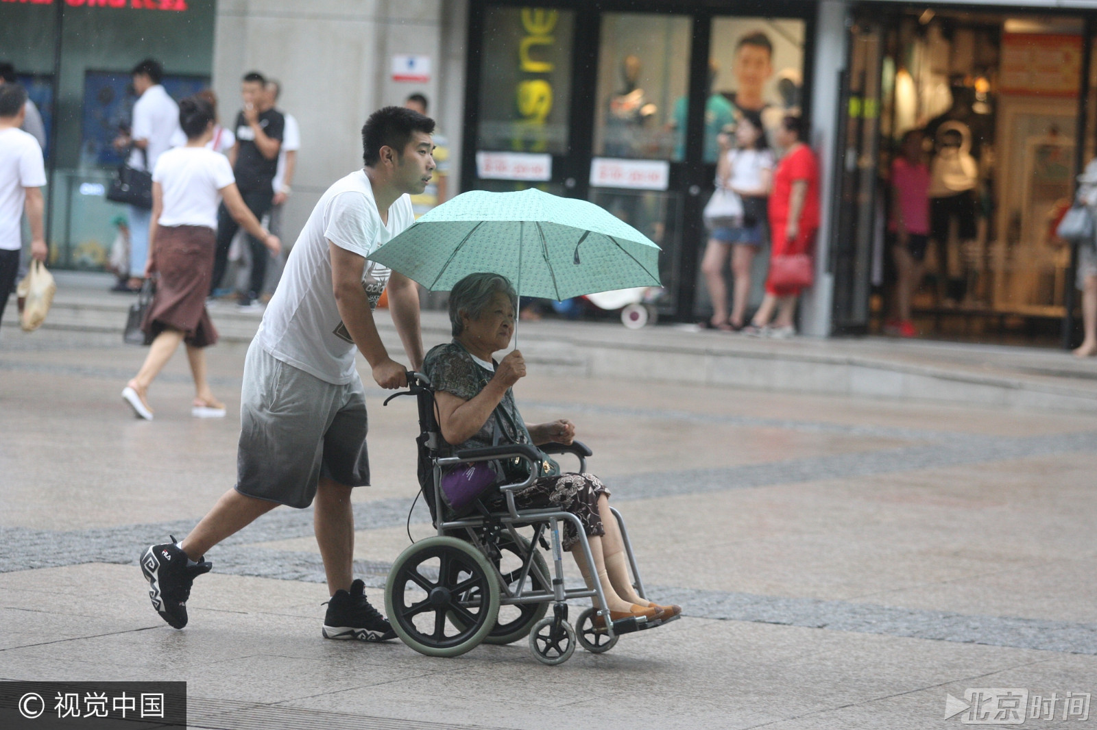 哈尔滨大雨突袭 男子雨中为老人撑伞获称赞