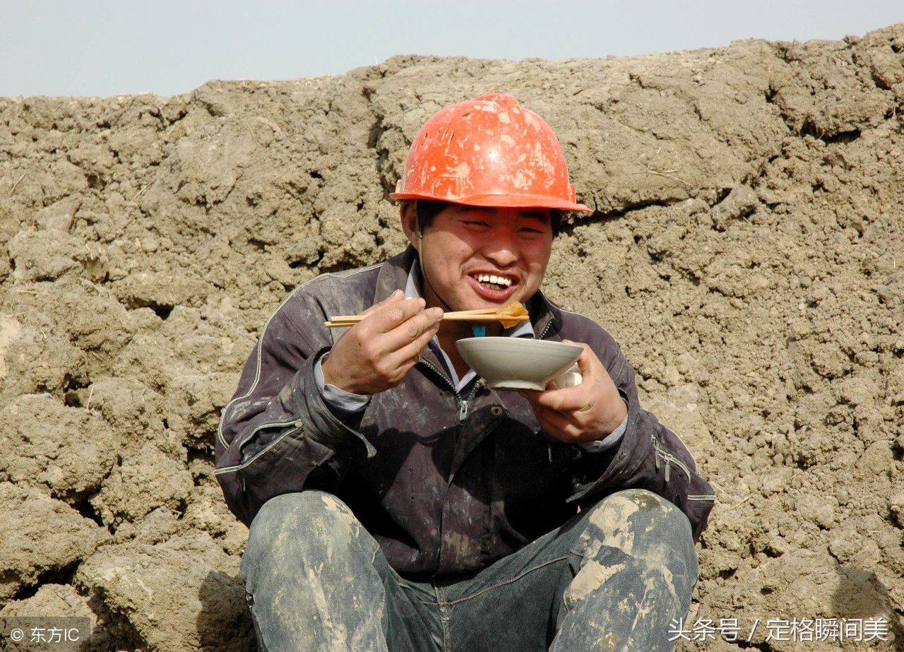 图为一建筑工地上的2名农民工在露天空地上面吃饭.