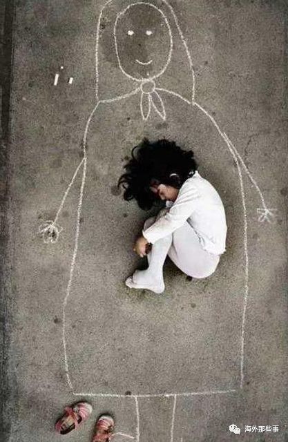 小女孩在伊拉克的孤儿院中,用粉笔在地上画了一个心中的妈妈,之后脱掉