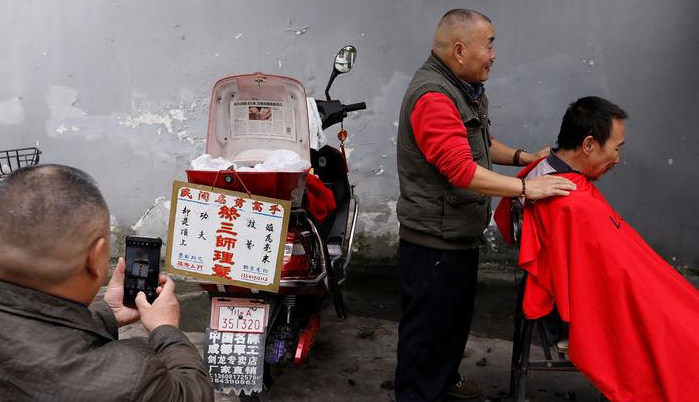 2017年11月18日，四川成都，62岁的街头理发师熊高武为顾客展示刀锋洗眼。熊高武自17岁起就在街头理发。人称“熊三师”的他有三个独门绝技：刀锋洗眼、跳三刀、舒筋。其中最令人称绝的就是刀锋洗眼也就是用锋利的刀片“扫”眼皮，据说只要体验过一次，就不会忘记。