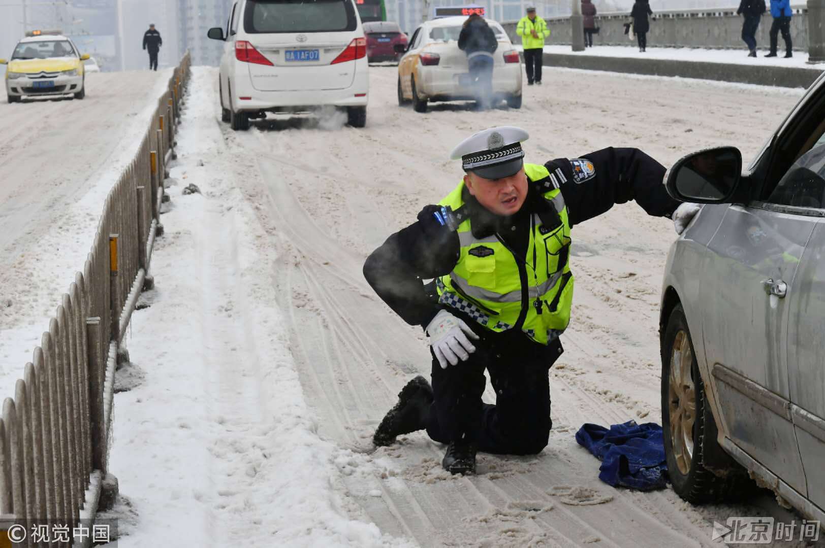 风雪中上演感动瞬间 武汉交警脱下上衣放冰面上推车