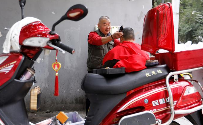 2017年11月18日，四川成都，62岁的街头理发师熊高武为顾客展示刀锋洗眼。熊高武自17岁起就在街头理发。人称“熊三师”的他有三个独门绝技：刀锋洗眼、跳三刀、舒筋。其中最令人称绝的就是刀锋洗眼也就是用锋利的刀片“扫”眼皮，据说只要体验过一次，就不会忘记。