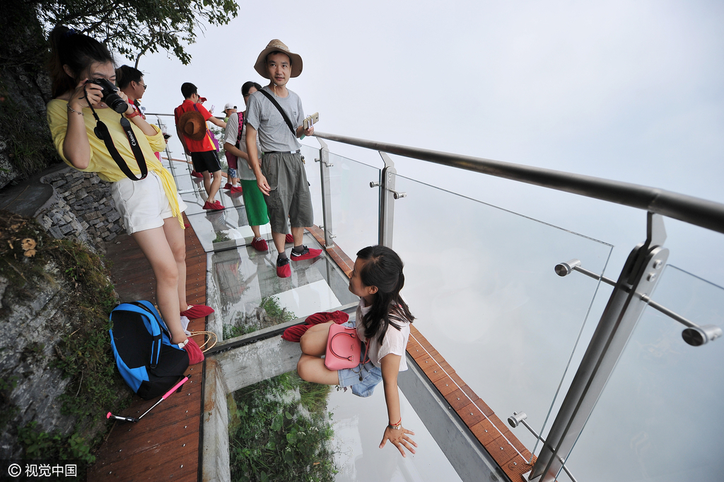 游客们在盘龙崖玻璃栈道上游玩拍照。