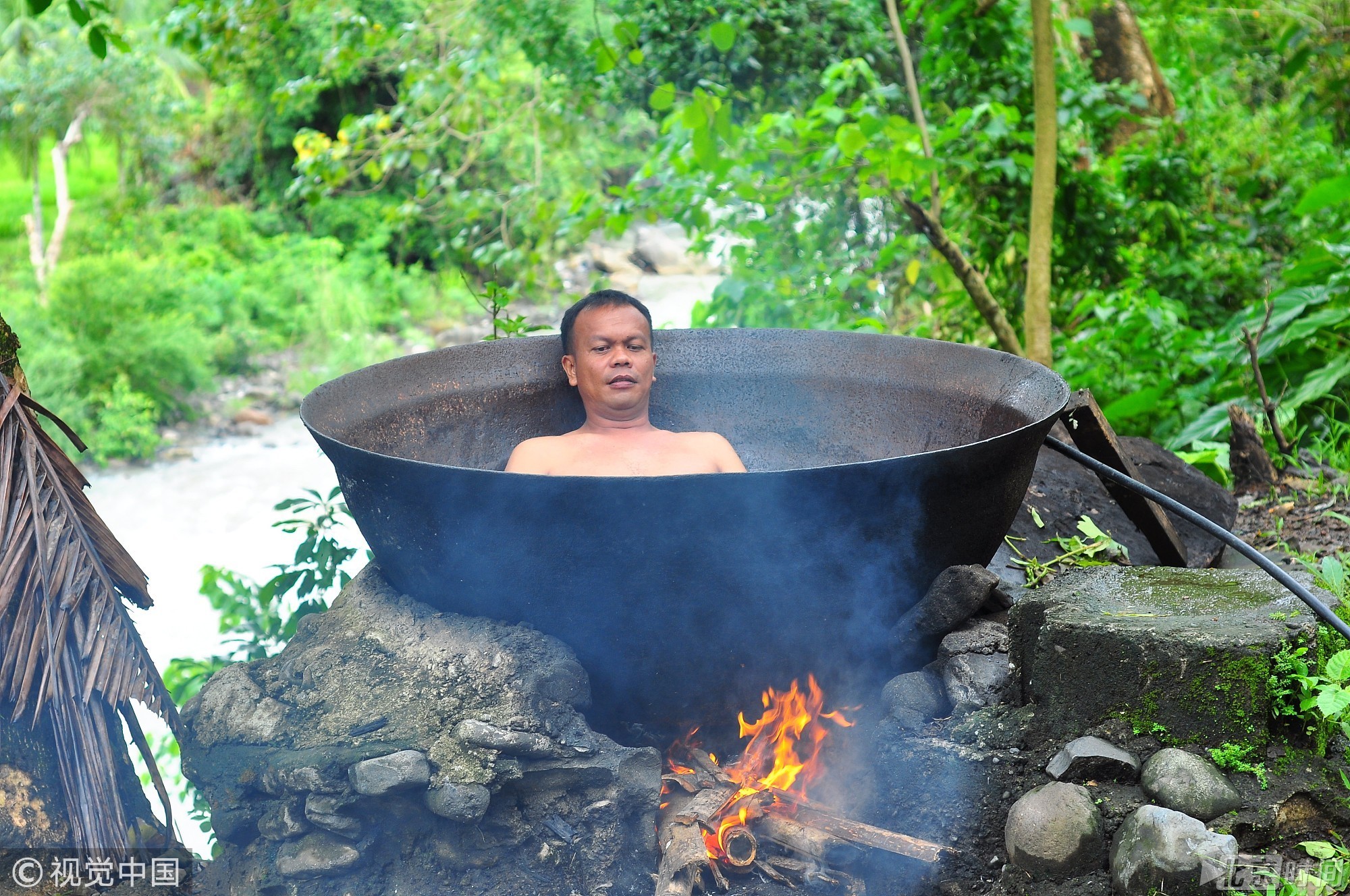 人躺在一口大锅中，下面点着柴火加热，体验一种独一无二被煮的感觉。