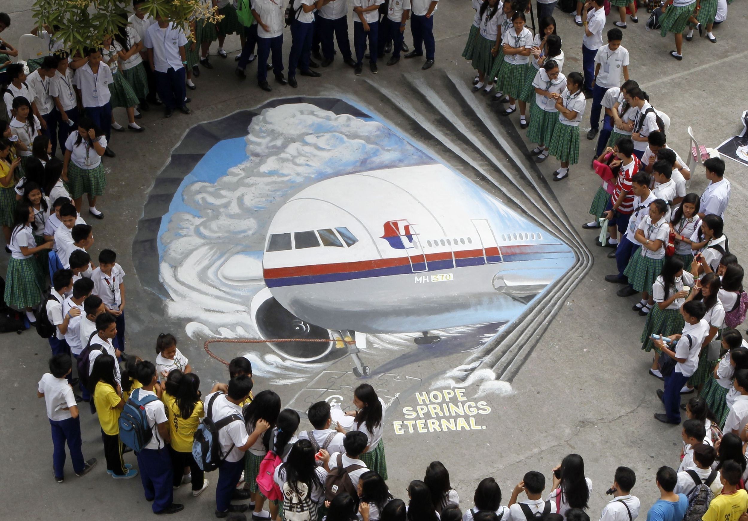 当地时间2014年3月17日，菲律宾马尼拉马卡迪，学生围观一群艺术家以马航失联航班为主题创作的3D作品。据悉，艺术家希望通过此举表达他们对于失联航班乘客家属的慰问和同情。