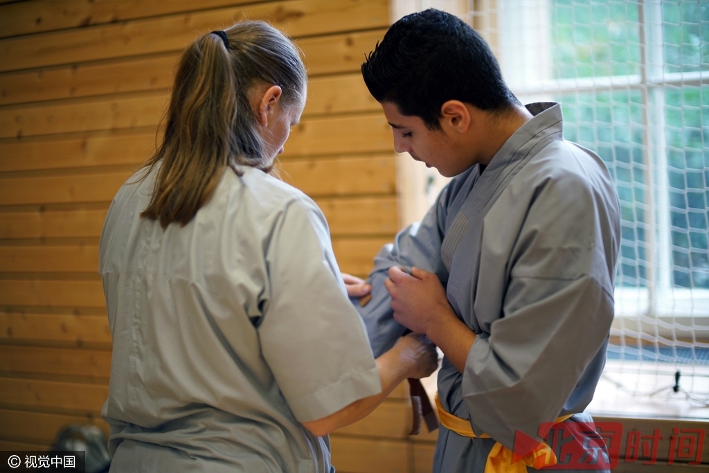 赫尔曼女士为来自叙利亚的未成年难民默罕默德整理训练服。