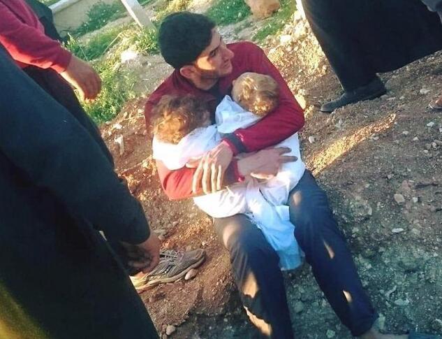 父亲抱着遭毒气杀害的龙凤胎强忍泪水