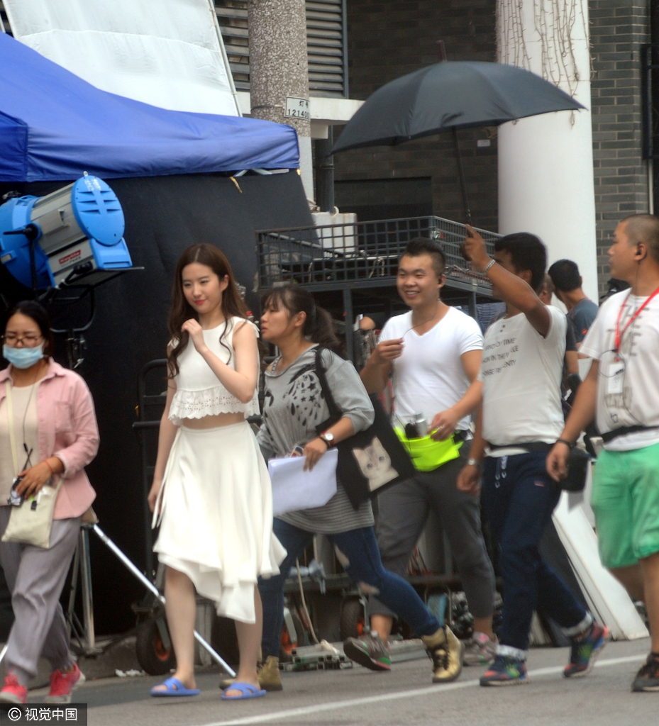 刘亦菲身穿飘逸白裙，脚底却踩着一双超市款式的蓝色澡堂拖鞋。