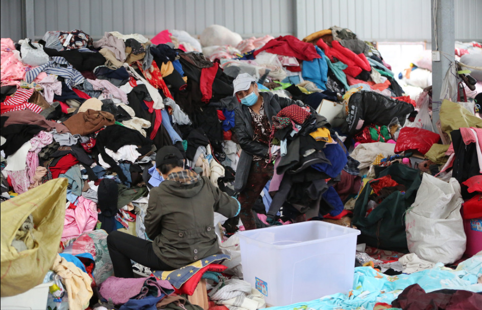 2016年10月13日，湖北省襄阳市，旧衣分拣中心里面堆放的旧衣物堆成了小山，工作人员根据衣服的成色、材质等进行分拣。