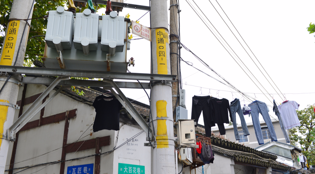 2016年10月04日，江苏省南京市，南京市秦淮区长乐路糖坊廊古街两侧挂满了晾晒的衣物，居民把衣服挂在电线上晾晒，情况十分危险。图为居民晾晒在电线及变压器附近的衣物。