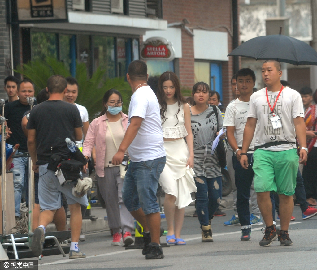 近日，刘亦菲在上海拍摄新剧，当天拍摄完毕后的刘亦菲快步返回房车，一路上有人为其打伞有人为其整理头发，还有工作人员在前领路浩浩荡荡一大批人护送排场相当大。然而穿着一身飘逸白裙的刘亦菲，脚底却踩着一双超市款式的蓝色拖鞋，时尚搭配风格令人相当傻眼。