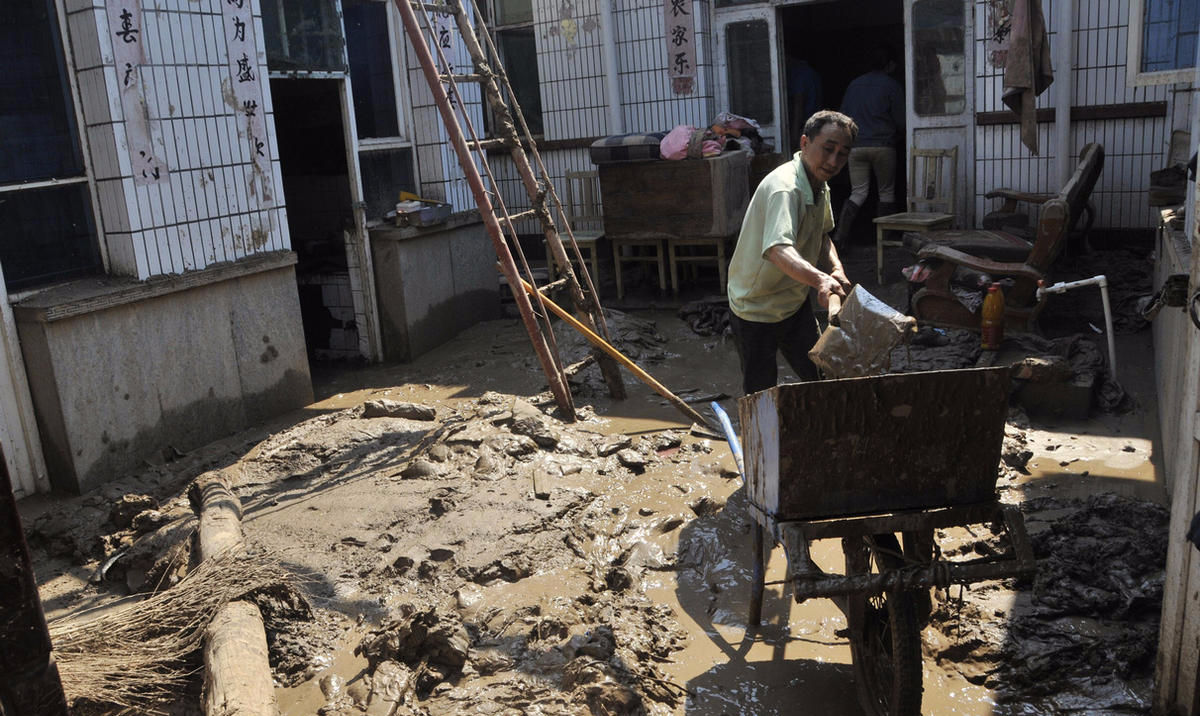 7月23日，井陉县小作镇南石门村村民在清理院子里的淤泥。新华社记者 巩志宏 摄