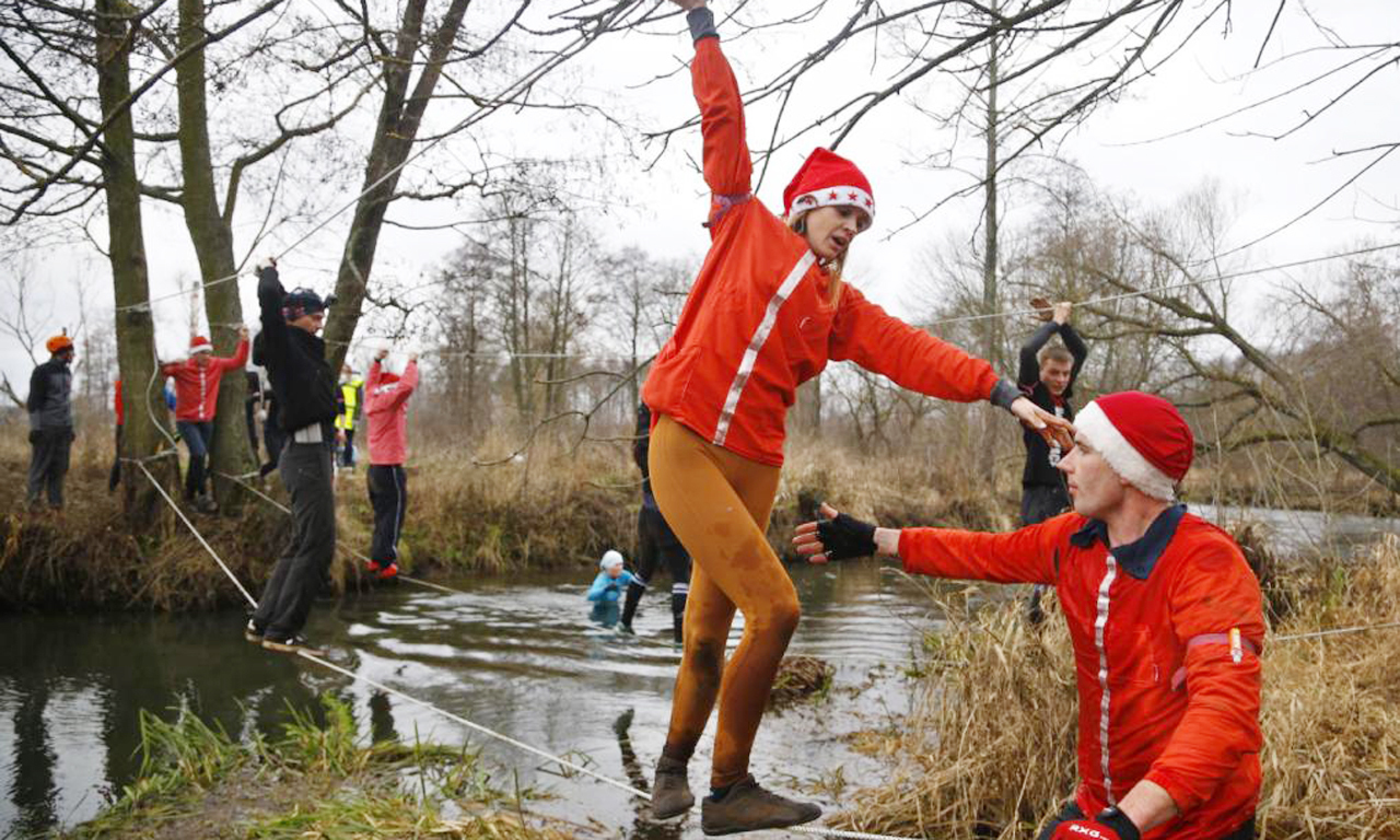 CMB比赛大约有6英里长，分为5个赛段并设有障碍。在比赛中，参赛者交替进行5公里障碍赛和山地骑行。每个团队必须使所有的路段都完成。图为选手通过铁丝“桥”。