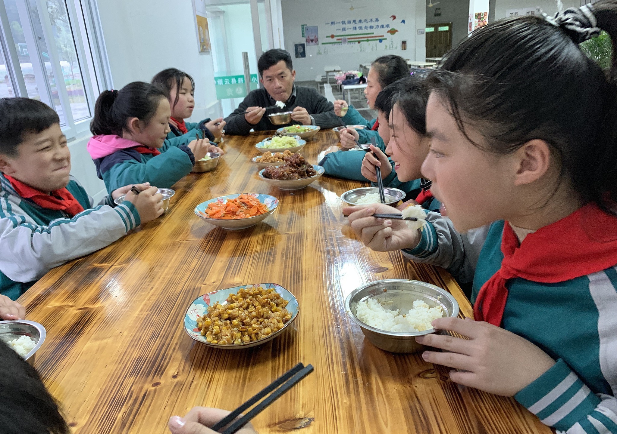 2019年4月4日中午,浙江丽水,缙云县新建小学的食堂内学生们用着午餐。在食堂的一个角落,有一张高出其他餐桌一半的条形木桌,校长刘勇武每周至少会有一顿会和8名学生在这张坐在同桌吃饭。