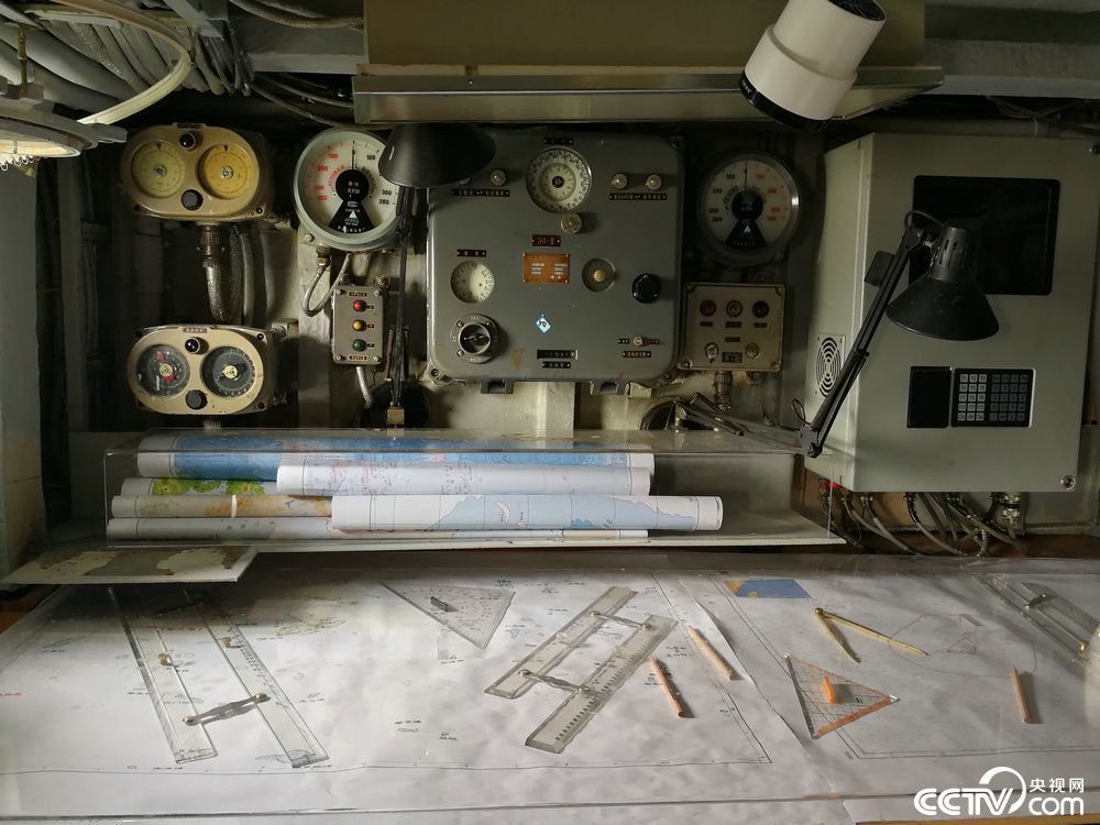 航程仪表盘前摆放着不同种类的地图和坐标工具。（记者 袁育堃 报道）