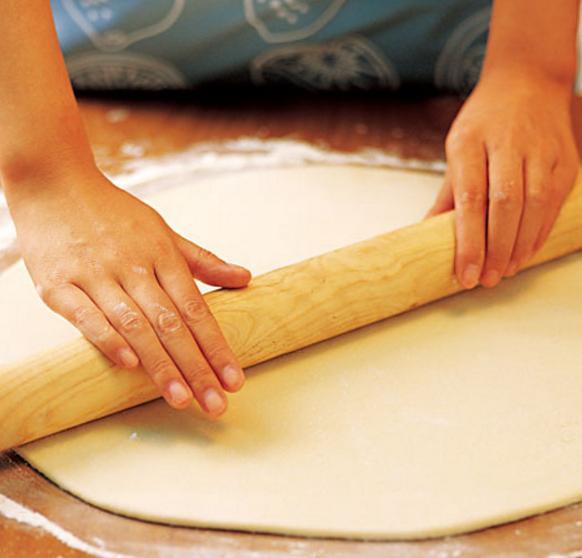 然后把面饼卷到擀面杖上,使劲往前擀,然后再拉回来,反复重复这个动作