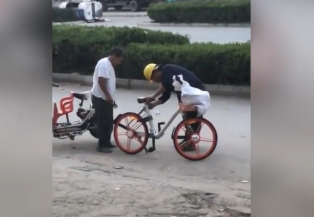 徐州新沂一带安全帽男子路边用钢锯锯共享单车