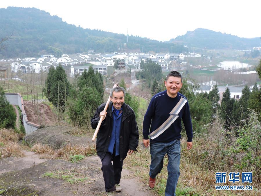 3月12日,四川省达州市渠县万寿乡灵感村“第一书记”、退伍军人廖阳(右一)和村民裴云俄行走在6组的山路上。身后是廖阳协助建成的远近有名的农旅基地徽派山水建筑“碧瑶山庄”。新华社发(邓良奎 摄)