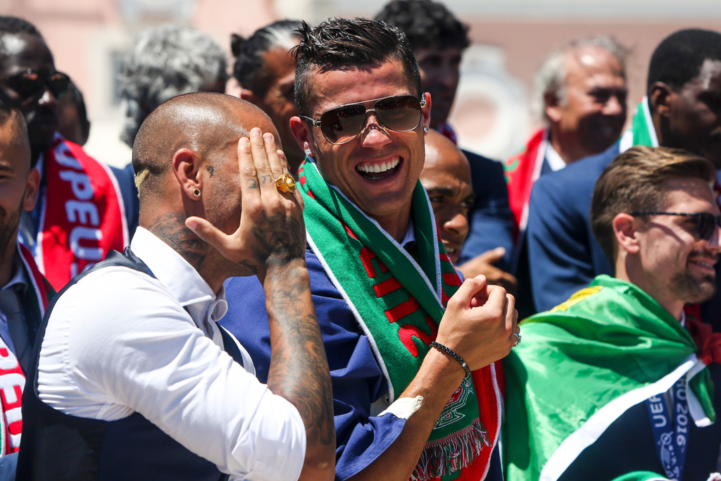 2016年7月11日，葡萄牙里斯本，2016年欧洲杯冠军葡萄牙队回到国内，全体队员和教练乘坐大巴游行并受到葡萄牙总统的接见，全城民众欢欣舞动狂欢庆祝。图为C罗和队友相谈甚欢