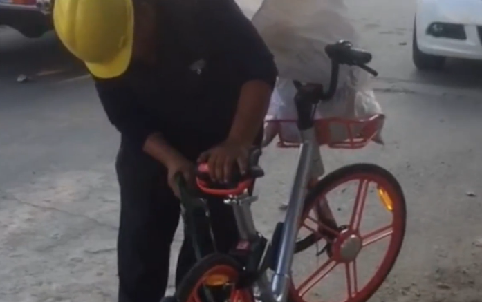 徐州新沂一带安全帽男子路边用钢锯锯共享单车