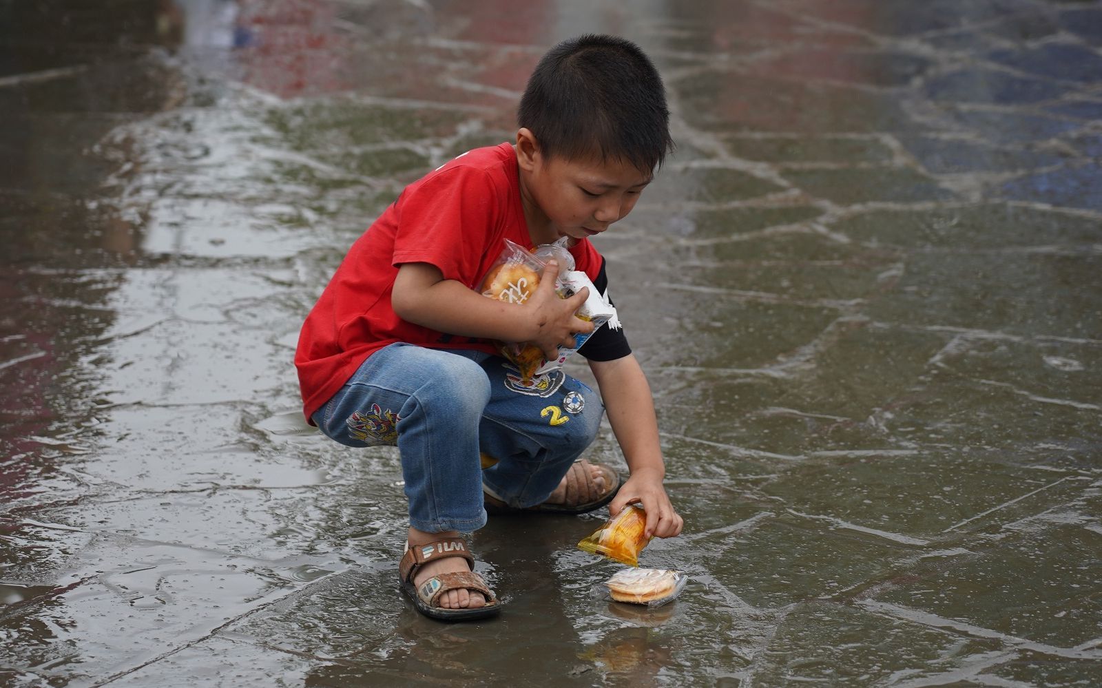 一位小朋友自己去领食物,掉地上了一个,赶紧蹲下捡起来.