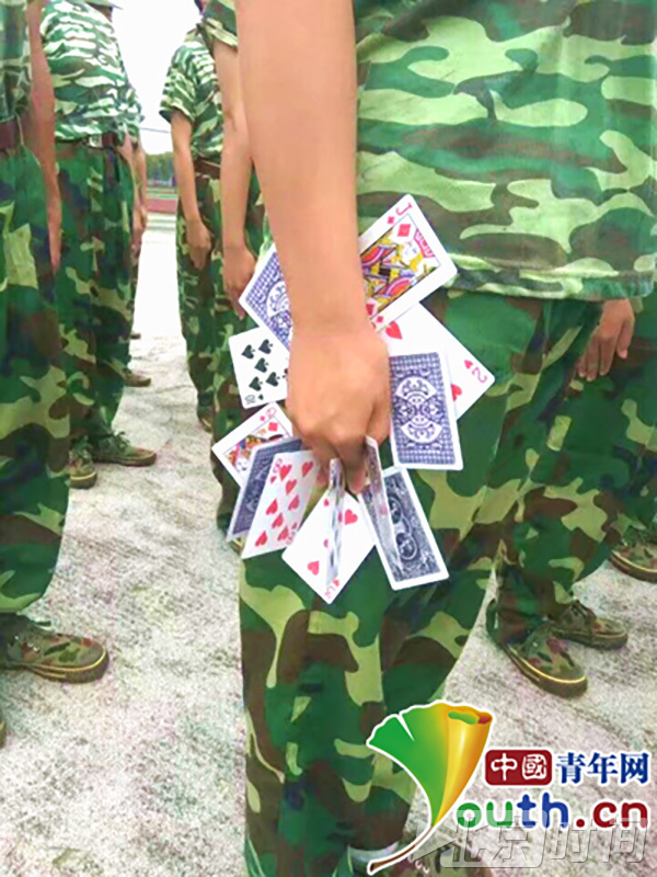 军训的教官们为了达到完美的训练效果，其训练手段可谓是“花样百出”。江西外贸外语职业学院的军训教官为了让新生的站姿更加挺拔，防止学生训练时偷懒，竟想出让新生“手夹10余张扑克牌”的花招。照片在网上发布后，有网友调侃说：“坐下就可以斗地主了。”（来源：中国青年网）