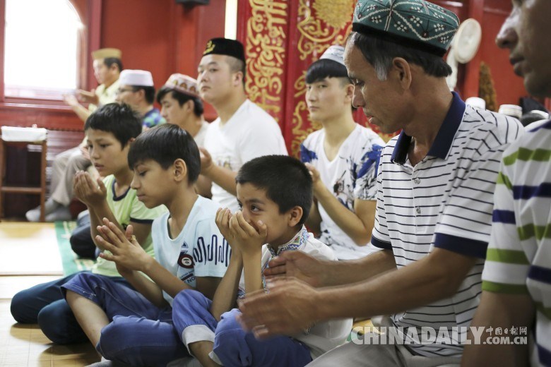 图为2016年7月6日，在北京牛街清真寺，8岁男孩乃斯热拉和家人一起参加会礼。