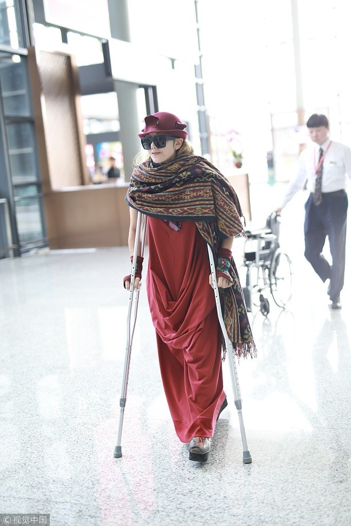 杨丽萍拄双拐现身机场 穿红裙笑容满面似少女 依然优雅美丽