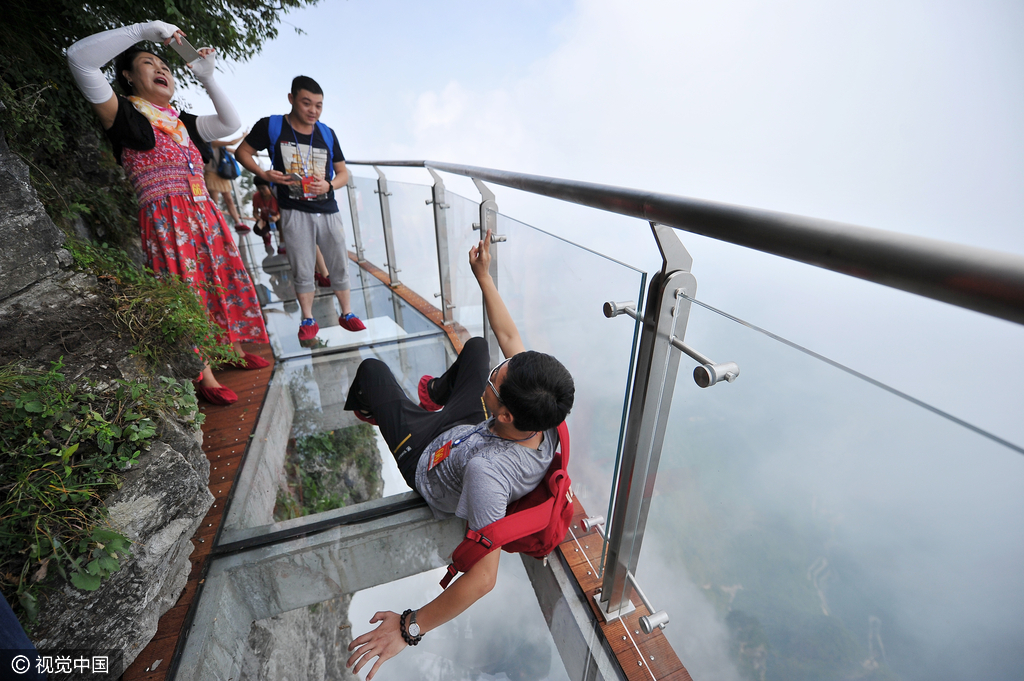 游客们在盘龙崖玻璃栈道上游玩拍照。