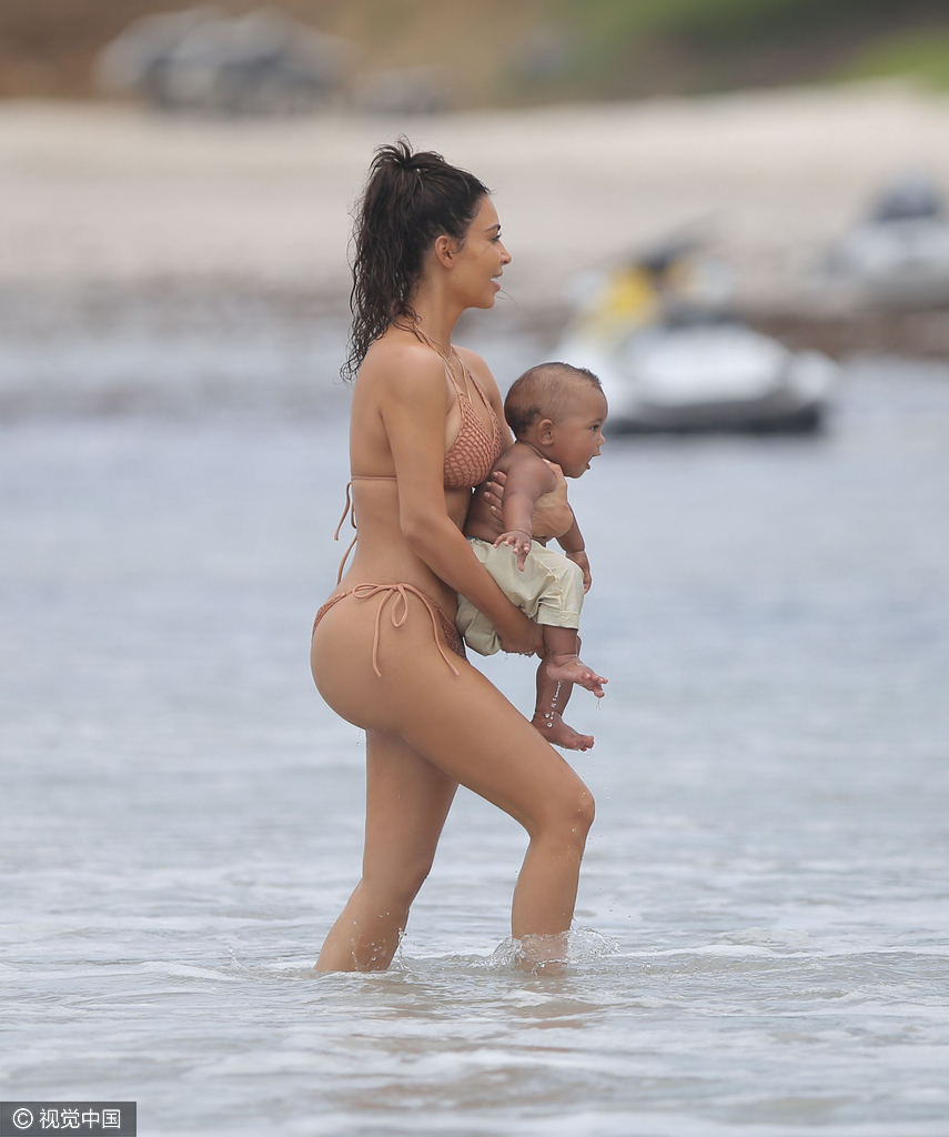 当地时间8月18日,金·卡戴珊(Kim Kardashian)带女儿小西北和儿子沙滩玩耍,卡戴珊身穿裸色系带比基尼,女儿与妈妈同款可爱十足,在沙滩上卡戴珊全程呵护幼子母爱爆棚,然而抢镜的还是翘臀。图为卡戴珊抱幼子。