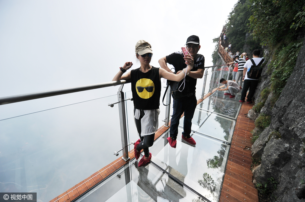 游客们在盘龙崖玻璃栈道上游玩拍照。